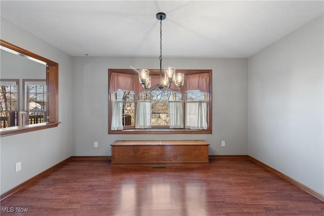 unfurnished dining area featuring dark wood-type flooring and an inviting chandelier