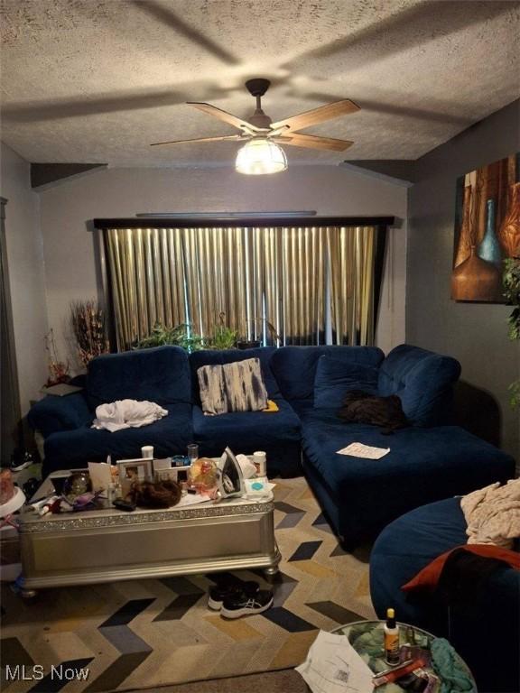 living room with ceiling fan and a textured ceiling