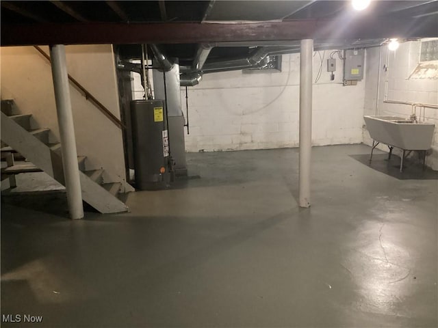 basement featuring electric panel, water heater, and sink