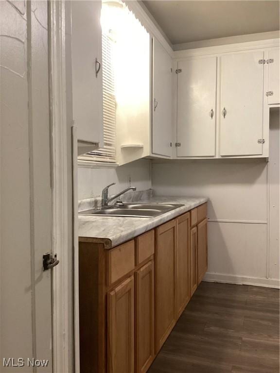 kitchen with dark hardwood / wood-style floors, white cabinetry, and sink