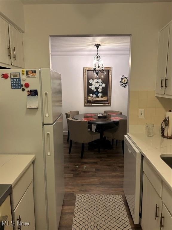 kitchen with decorative light fixtures, white cabinetry, decorative backsplash, dark wood-type flooring, and white appliances