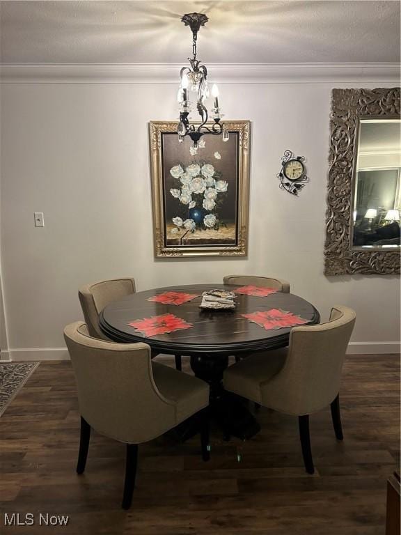 dining room featuring dark wood-type flooring, ornamental molding, and a chandelier