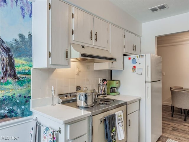 kitchen with stainless steel electric range, light hardwood / wood-style floors, decorative backsplash, and white fridge