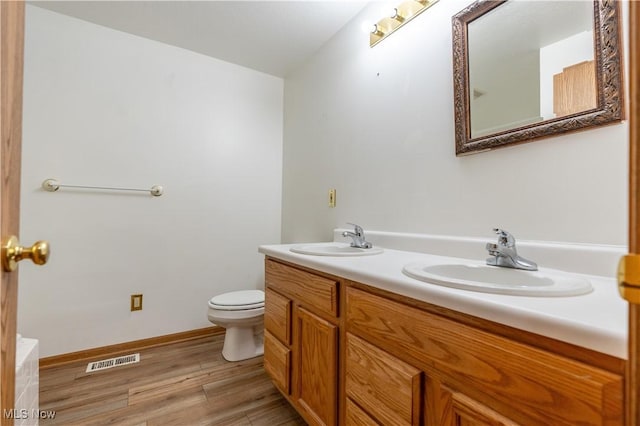 bathroom with hardwood / wood-style floors, vanity, and toilet