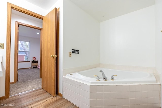 bathroom featuring hardwood / wood-style floors and tiled tub