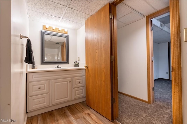 bathroom featuring a drop ceiling, vanity, and hardwood / wood-style floors