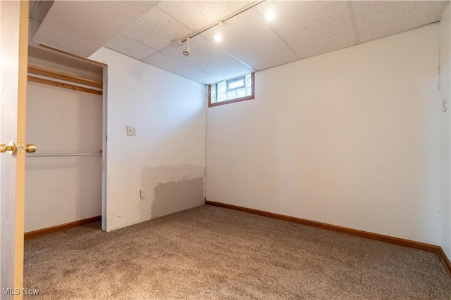 basement featuring a paneled ceiling, carpet floors, and rail lighting