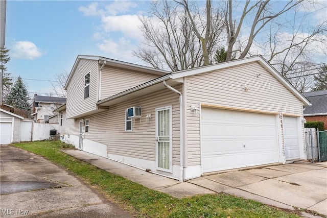 view of property exterior featuring a garage and a wall mounted AC