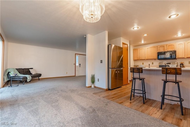 kitchen featuring kitchen peninsula, stainless steel fridge, a breakfast bar, an inviting chandelier, and range