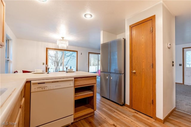 kitchen featuring white dishwasher, a notable chandelier, stainless steel fridge, and light hardwood / wood-style floors