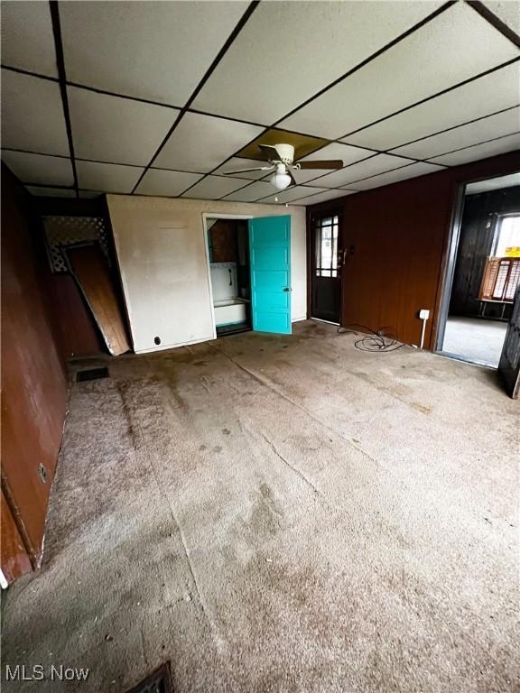 interior space with carpet flooring, ceiling fan, and a drop ceiling