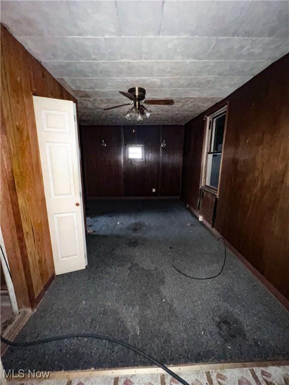 carpeted spare room with wooden walls and ceiling fan