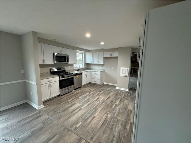 kitchen with white cabinetry, light hardwood / wood-style flooring, sink, and appliances with stainless steel finishes