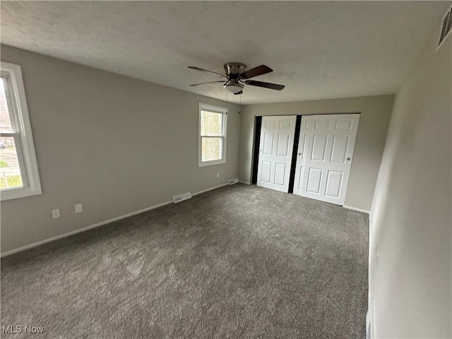 unfurnished bedroom with carpet flooring, ceiling fan, a closet, and multiple windows