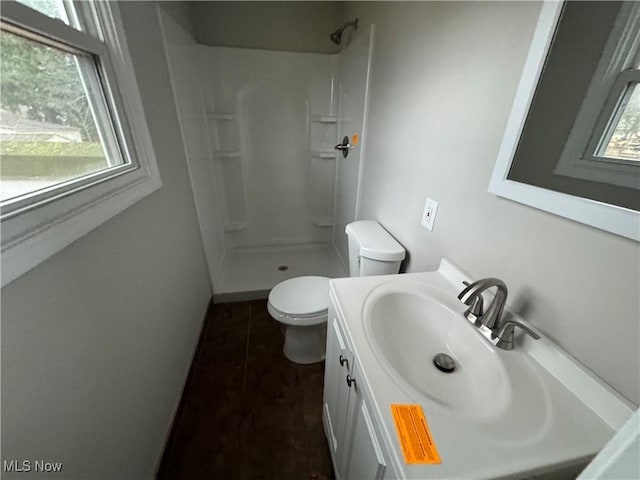 bathroom featuring tile patterned flooring, vanity, toilet, and a shower