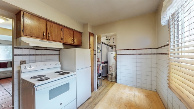 kitchen with tile walls, gas water heater, white appliances, and light wood-type flooring