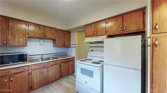 kitchen with backsplash, sink, white appliances, and light hardwood / wood-style flooring