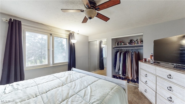 bedroom featuring a textured ceiling, dark carpet, and ceiling fan