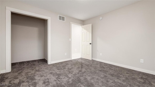 unfurnished bedroom with dark colored carpet and a closet