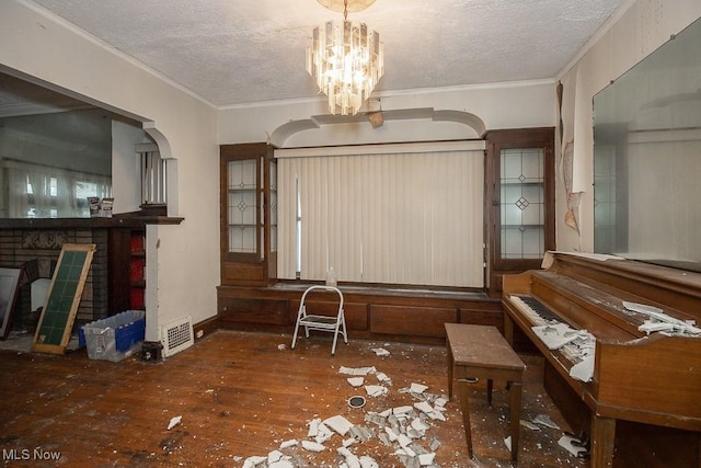 misc room featuring a chandelier, hardwood / wood-style floors, a textured ceiling, and ornamental molding