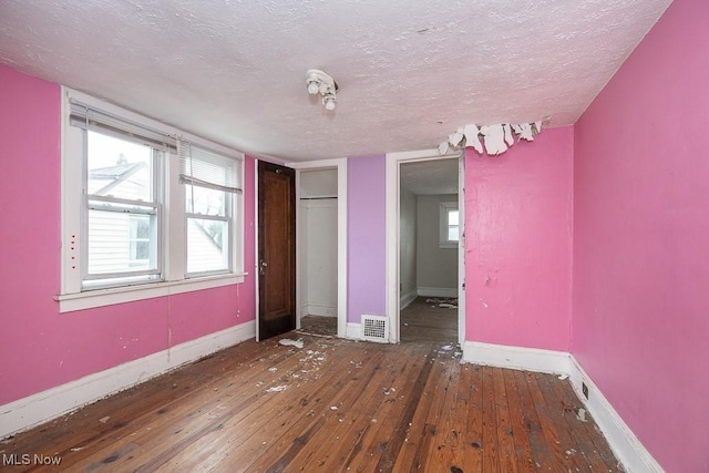 unfurnished bedroom with a textured ceiling and dark wood-type flooring