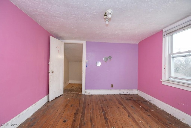 spare room featuring dark wood-type flooring and a textured ceiling