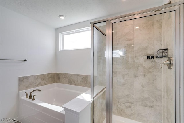 bathroom featuring a textured ceiling and shower with separate bathtub