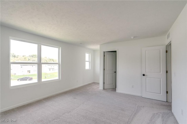 unfurnished bedroom featuring light carpet and a textured ceiling