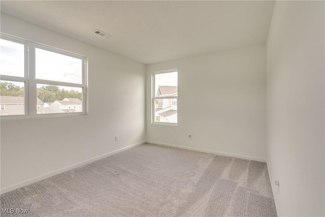 carpeted spare room featuring plenty of natural light