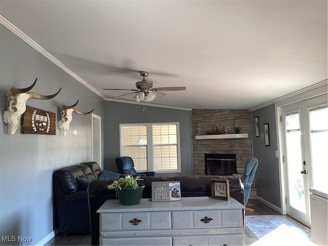 living room with ceiling fan, a stone fireplace, ornamental molding, and vaulted ceiling