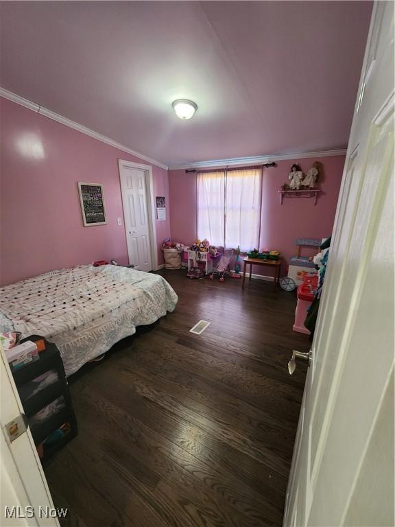 bedroom with ornamental molding and dark wood-type flooring