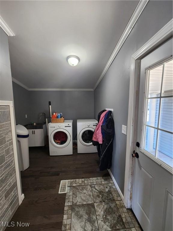 clothes washing area with ornamental molding, a wealth of natural light, and washing machine and clothes dryer