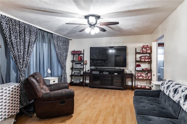 living room with ceiling fan, light hardwood / wood-style floors, and a textured ceiling