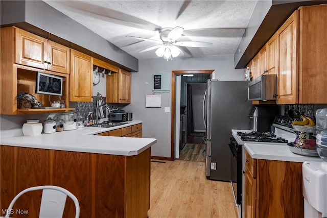 kitchen featuring kitchen peninsula, appliances with stainless steel finishes, tasteful backsplash, and sink