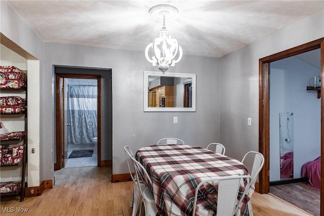 dining space featuring light wood-type flooring, a textured ceiling, and a chandelier