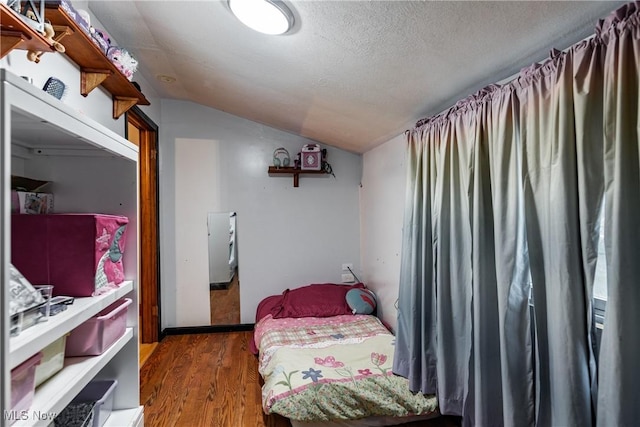 bedroom featuring a textured ceiling, vaulted ceiling, and dark wood-type flooring