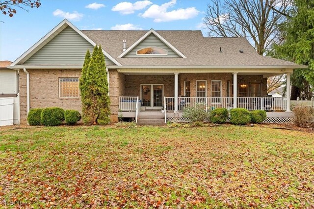 rear view of property with covered porch, brick siding, and a lawn