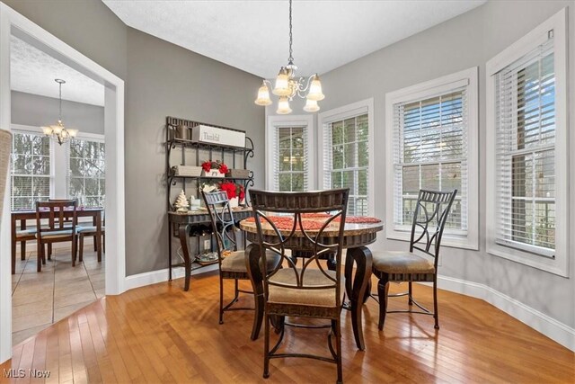 dining room featuring a chandelier, light wood finished floors, and baseboards