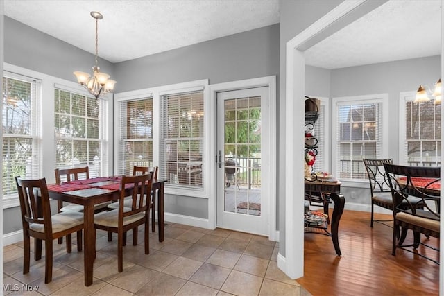 tiled dining room featuring baseboards, a notable chandelier, and a textured ceiling