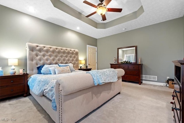 bedroom featuring recessed lighting, light carpet, baseboards, visible vents, and a tray ceiling