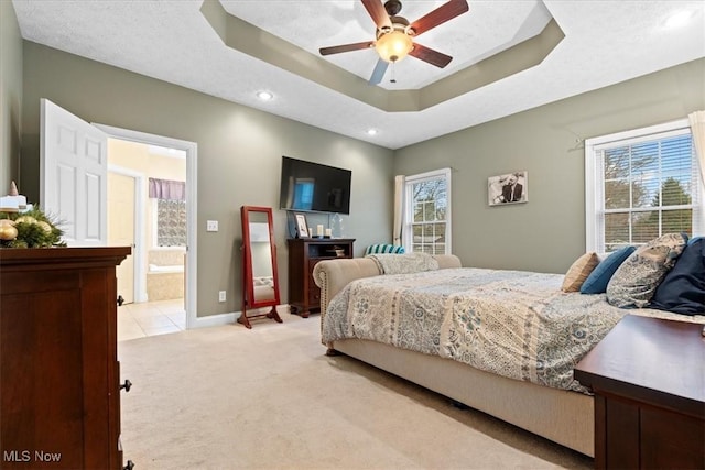 bedroom with recessed lighting, light carpet, multiple windows, and ensuite bathroom