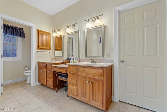 bathroom featuring toilet, double vanity, a sink, and tile patterned floors