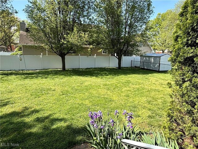 view of yard featuring an outdoor structure, a fenced backyard, and a storage shed