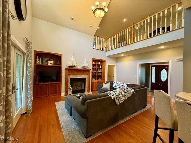 living area featuring recessed lighting, a fireplace, high vaulted ceiling, built in features, and wood finished floors
