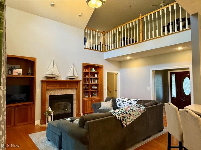 living area featuring recessed lighting, wood finished floors, a fireplace, and a towering ceiling