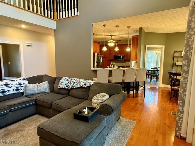living area featuring visible vents, light wood-style flooring, and a towering ceiling