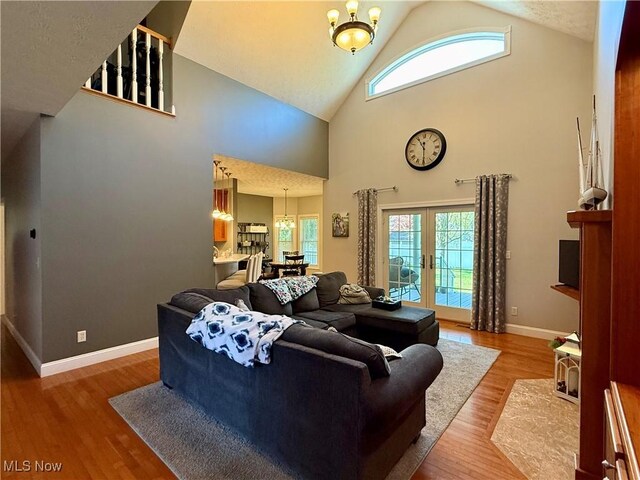 living area with high vaulted ceiling, wood finished floors, and a healthy amount of sunlight