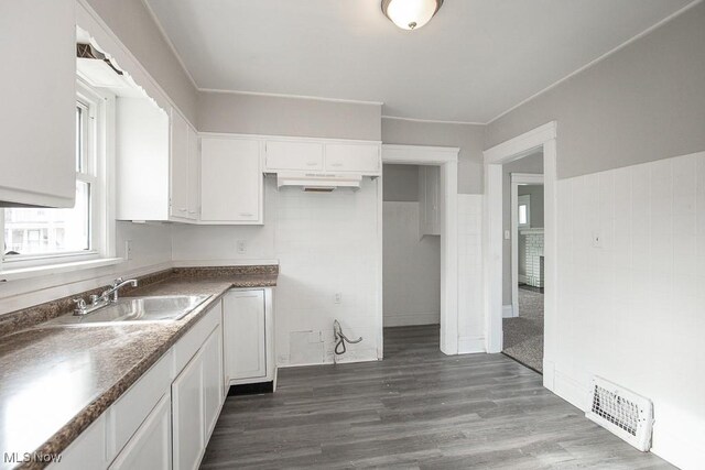 kitchen with dark hardwood / wood-style flooring, crown molding, sink, and white cabinets