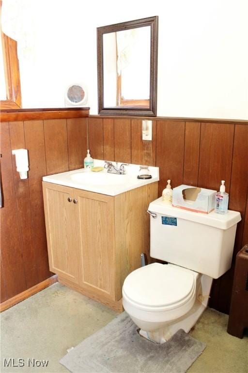 bathroom with wood walls, vanity, and toilet