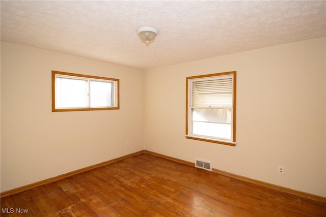 spare room with hardwood / wood-style flooring, a healthy amount of sunlight, and a textured ceiling